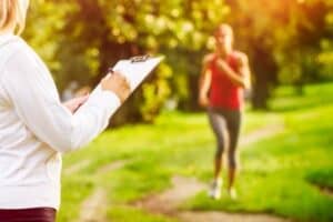 woman with clipboard waiting on woman running without technology